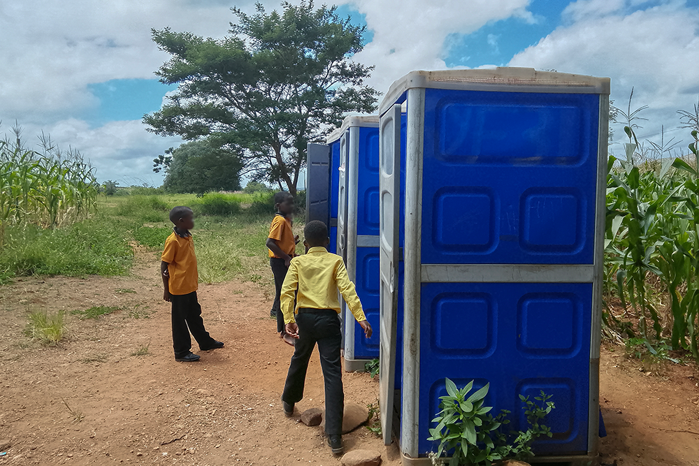 Three learners standing outside the chemical toilets at Dzivhani Primary School in Thohoyandou, Limpopo, South Africa. Photo: Chris Gilili